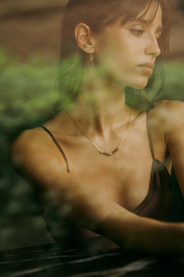 A fine gold Reflections necklace catching golden-hour light on the collarbone, Sofia Godinho