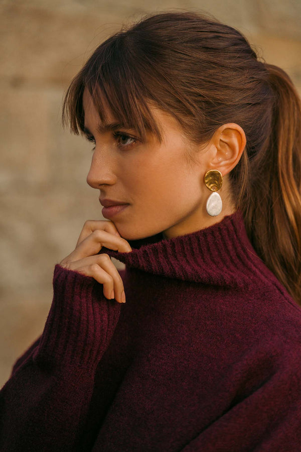 A woman wearing a modern pearl earring with a burgundy knit, the modern way to wear pearls by Sofia Godinho