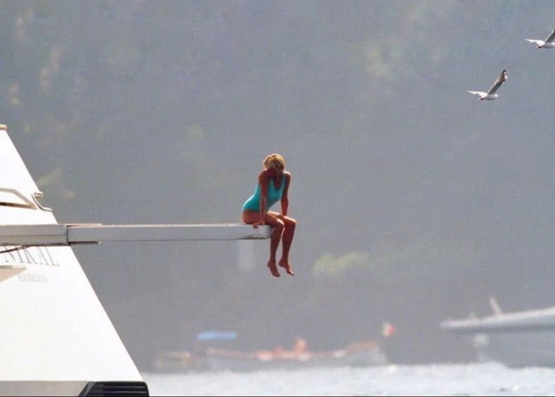 Princess Diana in a turquoise swimsuit sitting on a diving board over the sea, timeless swimwear icon