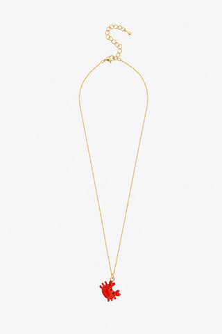 A delicate gold chain necklace featuring a small coral-shaped pendant in a warm coral-pink color, displayed against a solid light gray background.